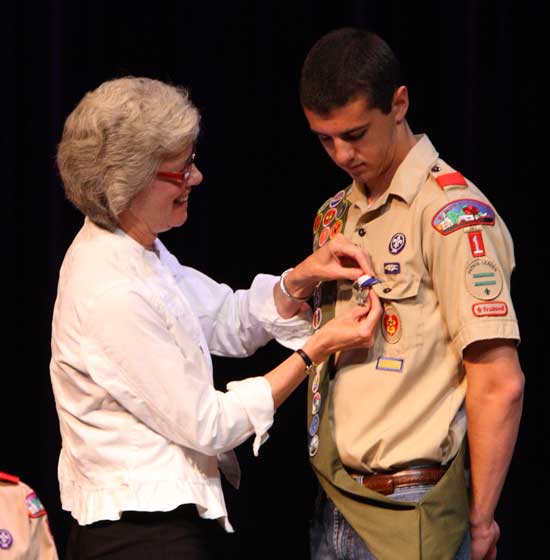 Carol Landry attaches the Eagle Scout pin to son Ben's uniform.