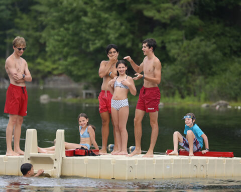 From left: Jackson Whitley, Jeremy Brown (in water), Julianno Liuzzi, Shane Trabulsi, Gianna Baer, Shea Van Cleef, and Jack Hogan hang out on a raft during swimming lessons at the town beach, Aug. 5. (Photo by Lisa Aciukewicz)