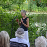 Lucy Wallace holds up an autograph book from her childhood at the Old Frog Pond Farm storytelling event, Aug. 16. She shared a quote from a teacher who wrote that Wallace had brought “sunshine and smiles” to the classroom. That note made her realize she “could be her own person,” and she gained self-confidence after growing up often feeling dismissed among her siblings. (Photo by Hannah Taylor)