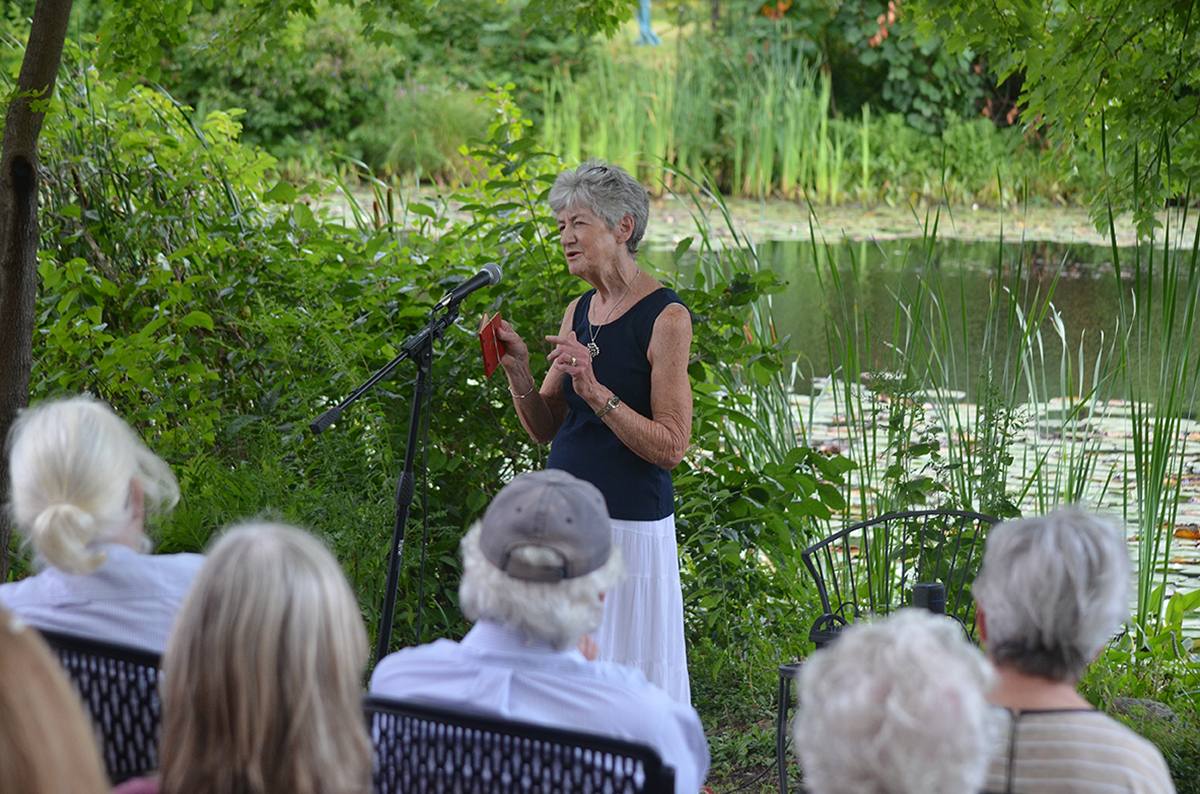Lucy Wallace holds up an autograph book from her childhood at the Old Frog Pond Farm storytelling event, Aug. 16. She shared a quote from a teacher who wrote that Wallace had brought “sunshine and smiles” to the classroom. That note made her realize she “could be her own person,” and she gained self-confidence after growing up often feeling dismissed among her siblings. (Photo by Hannah Taylor)