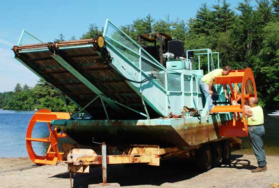 Department of Public Works employees Jeff Greco (left) and Bill Card adjust one of the paddlewheels on the weed harvester at the town beach on Bare Hill Pond to prepare for its annual launch. (Photo by Sue Fitterman)